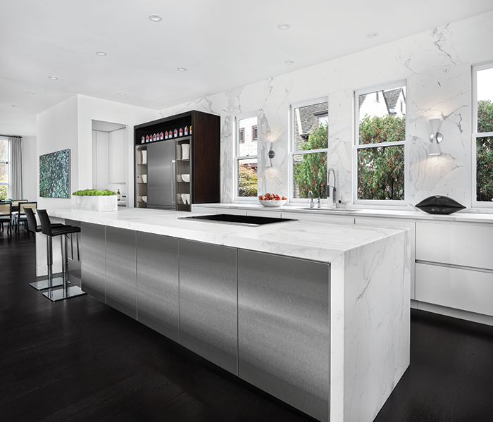 White honed marble is featured on the kitchen walls and the stainless-steel island's waterfall countertop.