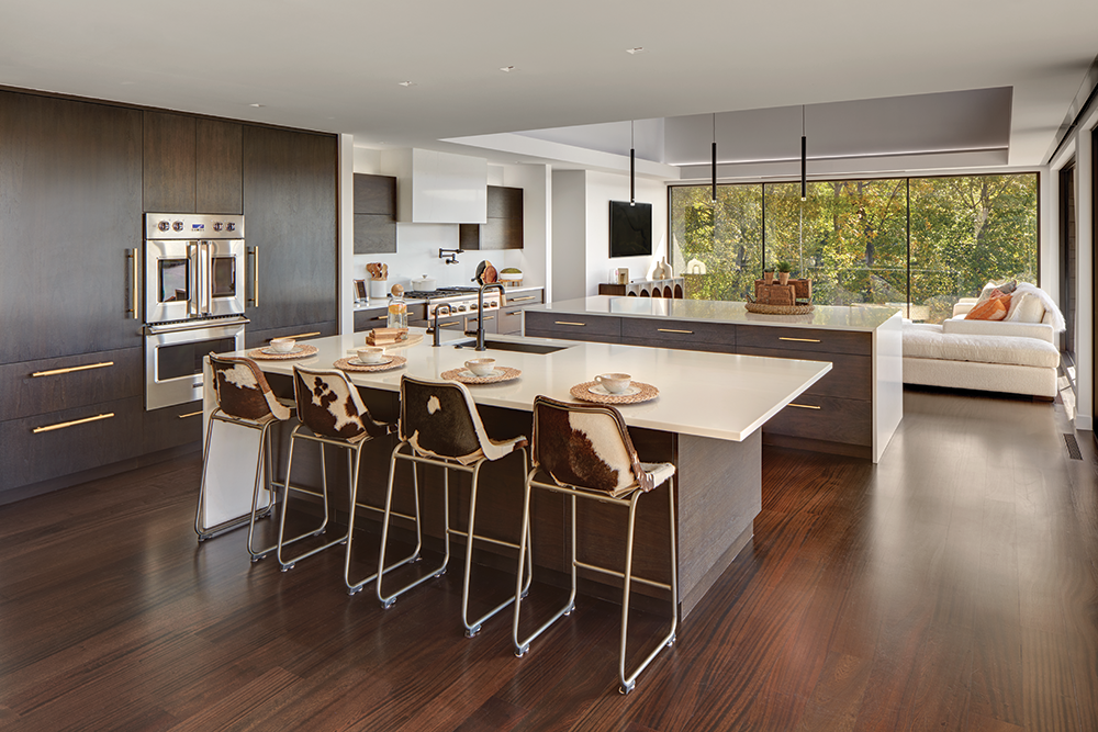 The kitchen has a welcoming feel with its nearby sitting area, cozy stools, and uninterrupted views of the outdoors.